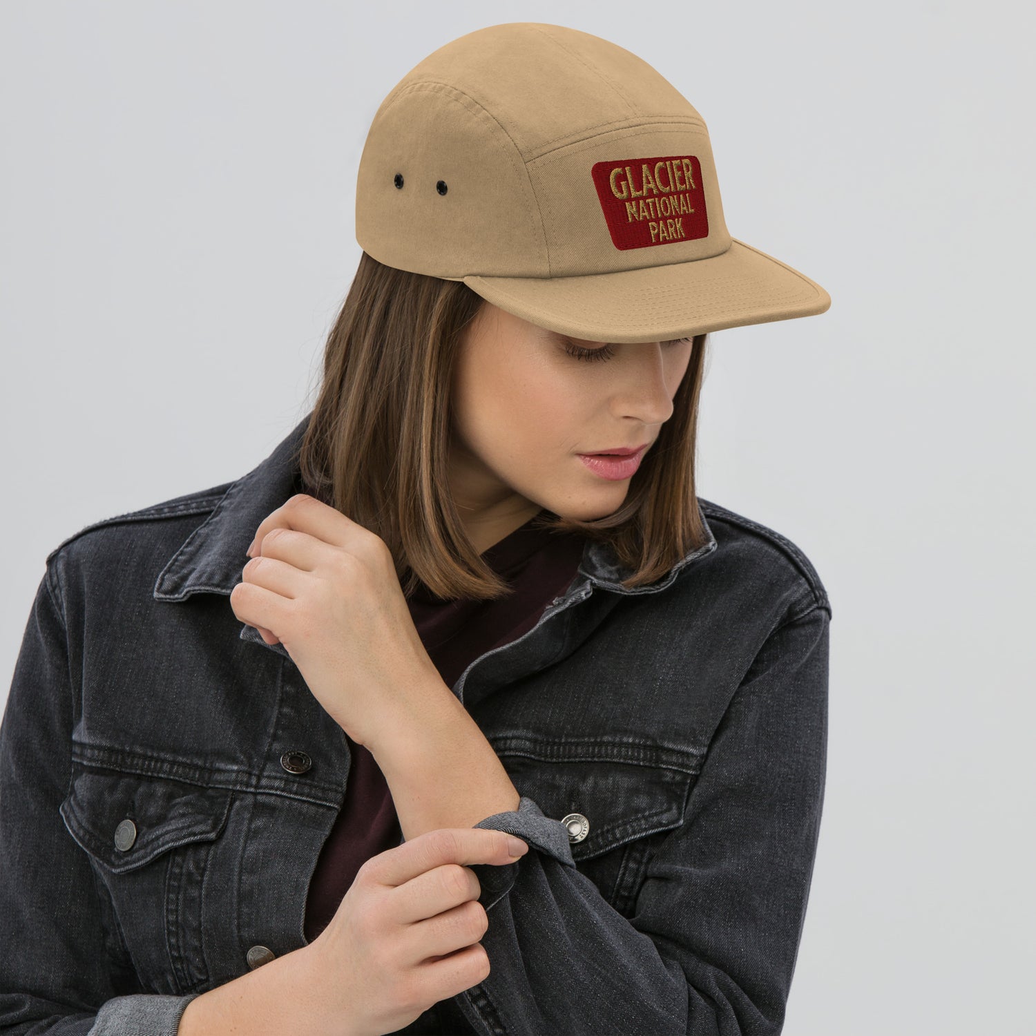 Person wearing a beige cap with 'Glacier National Park' logo on a light gray background