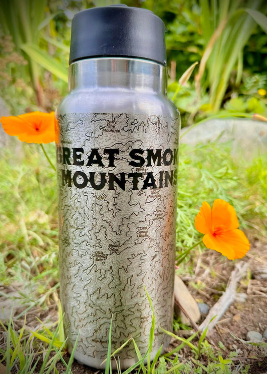 Silver water bottle with 'Great Smoky Mountains' text and map design, surrounded by orange flowers and greenery.