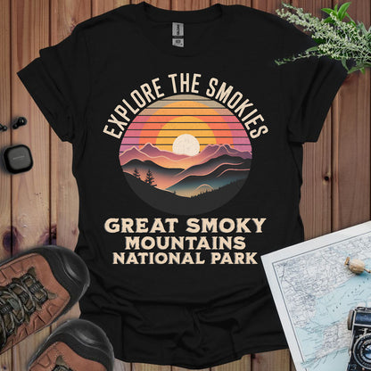 Black t-shirt with 'Explore the Smokies, Great Smoky Mountains National Park' design on a wooden surface.