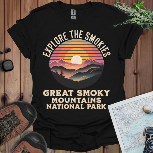 Black t-shirt with 'Explore the Smokies, Great Smoky Mountains National Park' design on a wooden surface.