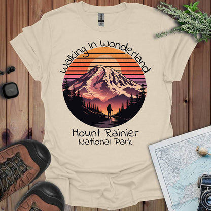 Beige t-shirt with Mount Rainier National Park design on a wooden surface with hiking gear.