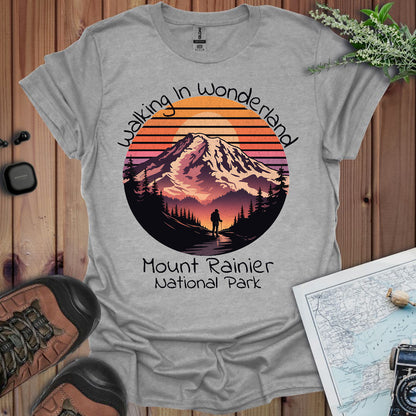 Gray t-shirt with Mount Rainier National Park design on a wooden surface with hiking gear.