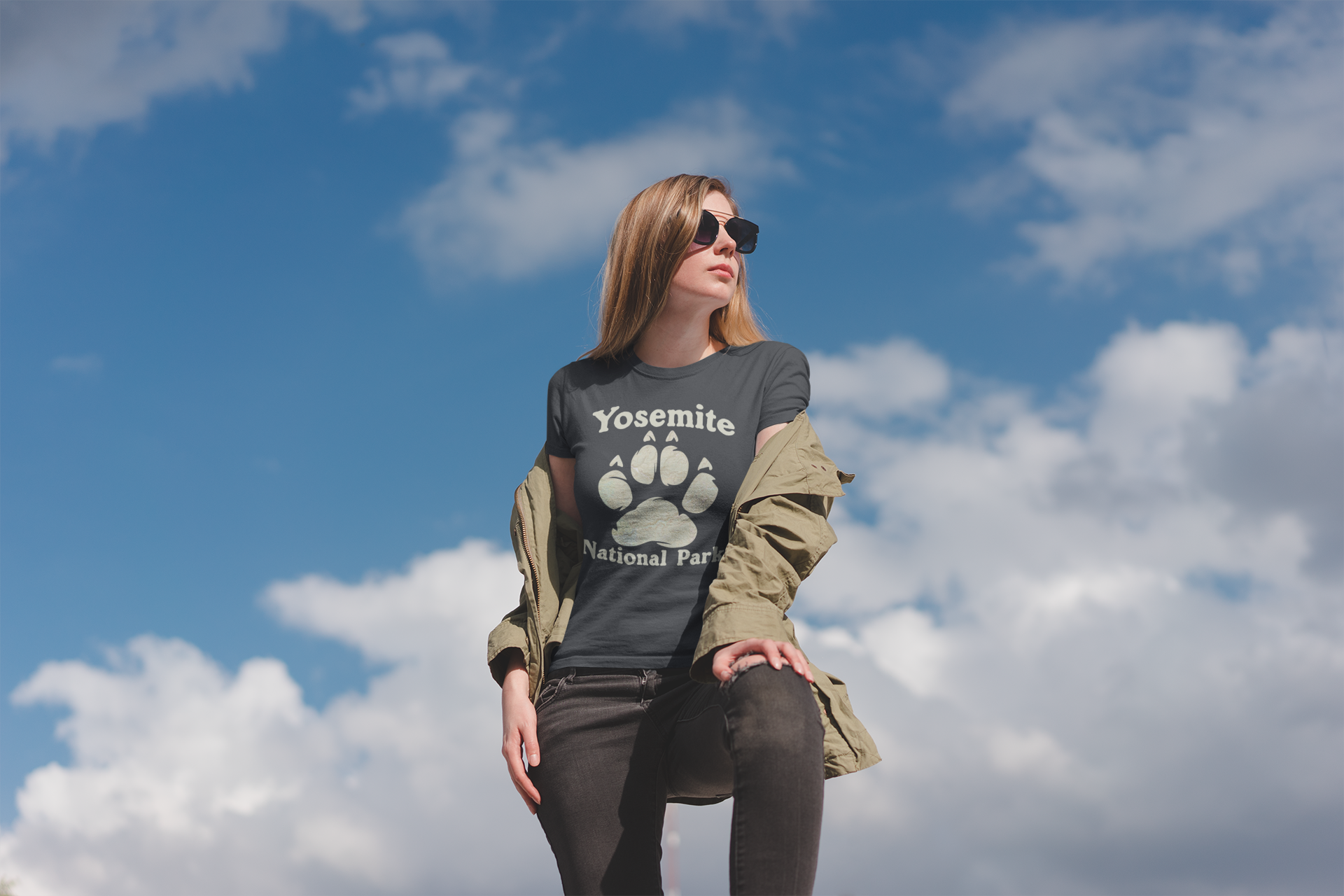 Woman wearing a 'Yosemite National Park' t-shirt against a blue sky with clouds