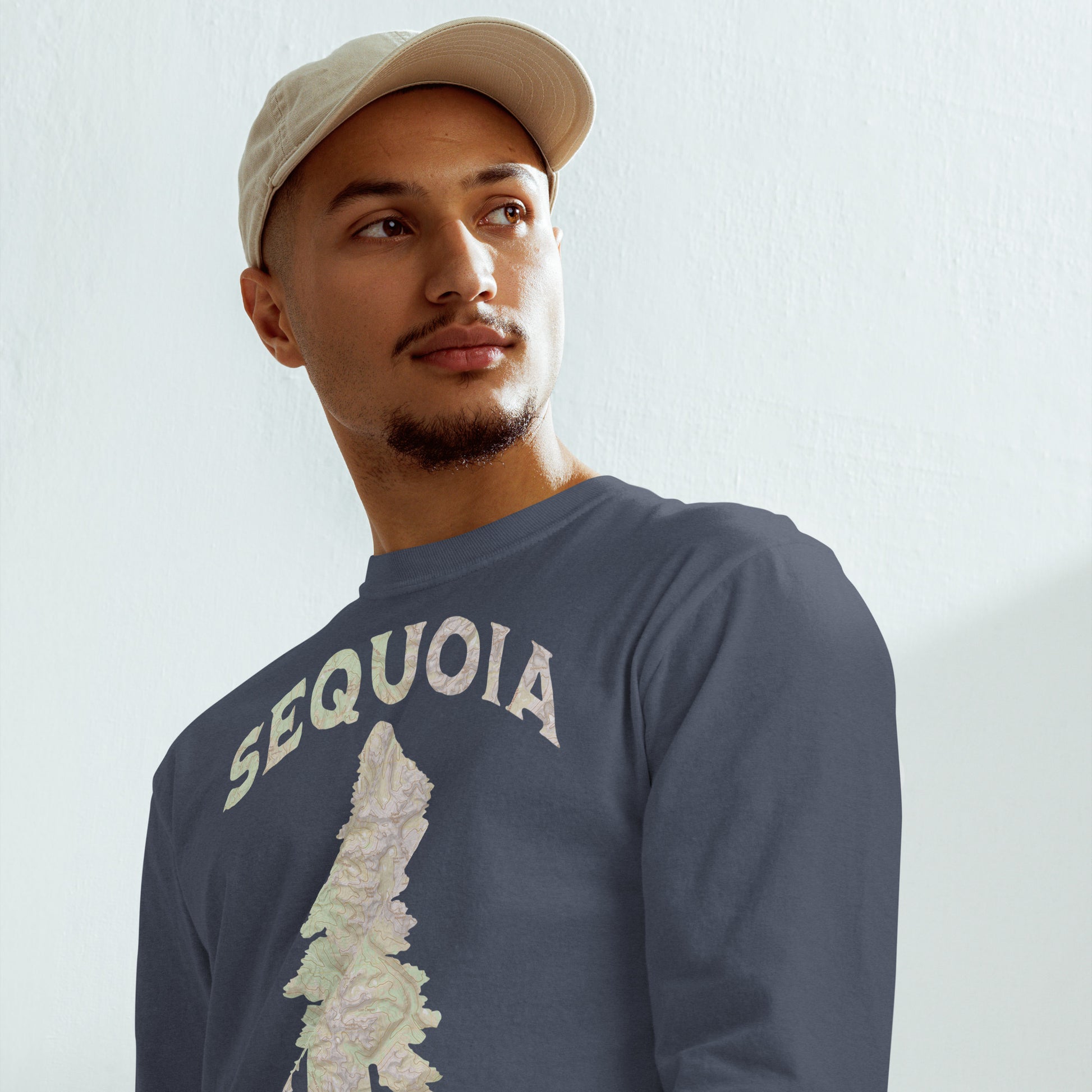 Man wearing a blue 'Sequoia' t-shirt and beige cap against a white background